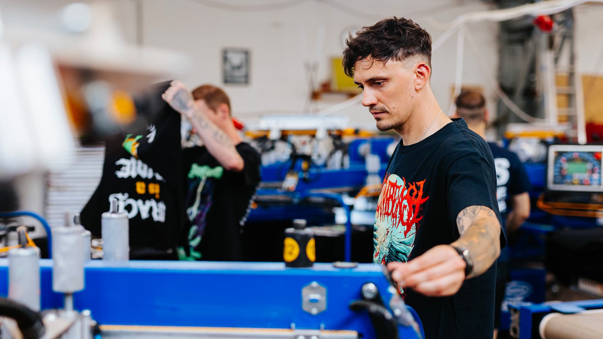 Siebdruck-Operatoren erstellen individuellen Metal-Band-Merchandise in der Real Pimp Budapest Werkstatt