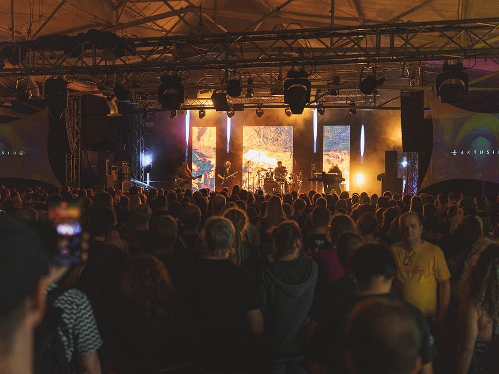 Indoor metal festival concert with merchandise sales supporting European tour bands