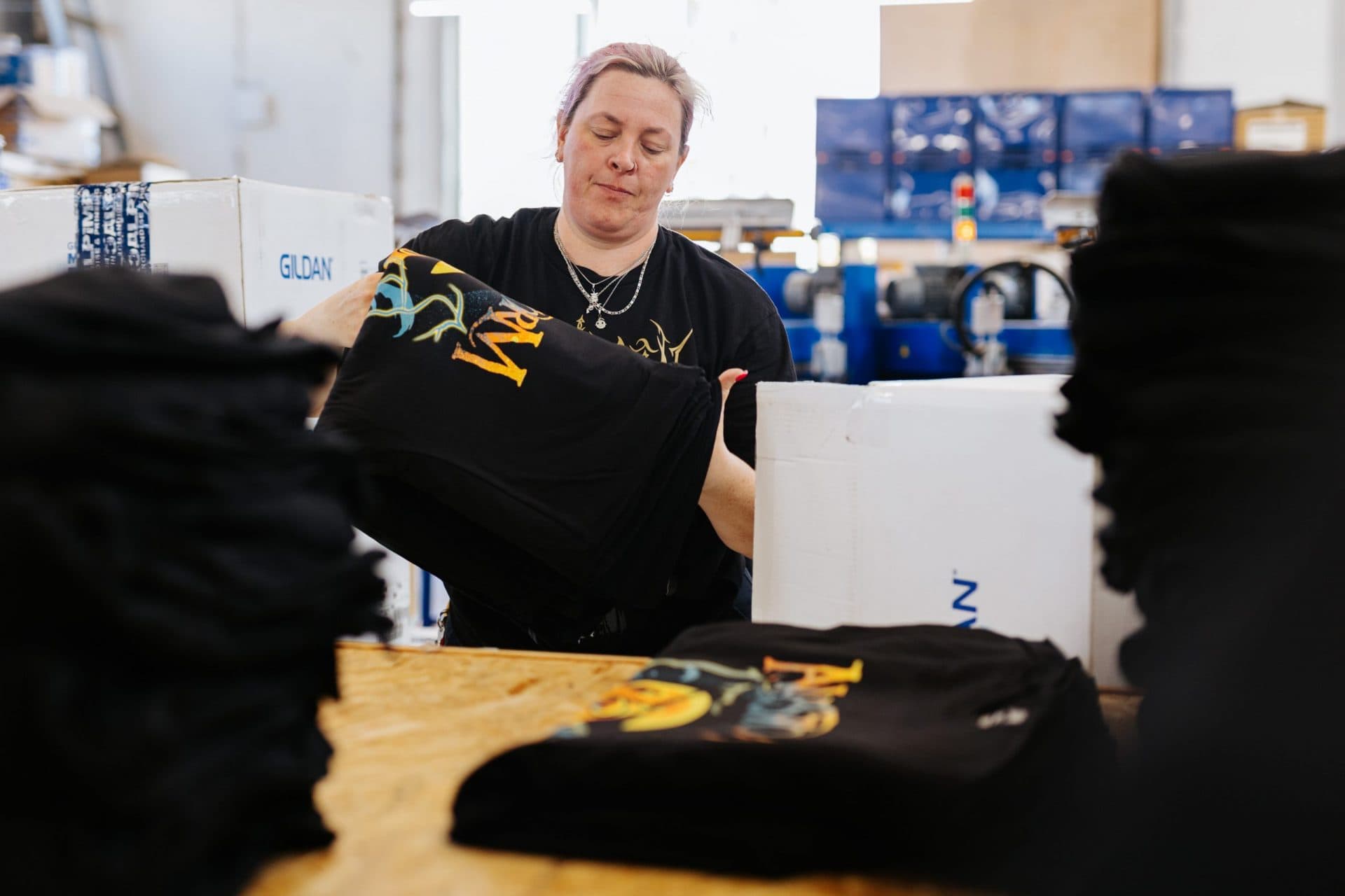 Warehouse team member folding band merchandise for professional tour shipment packing