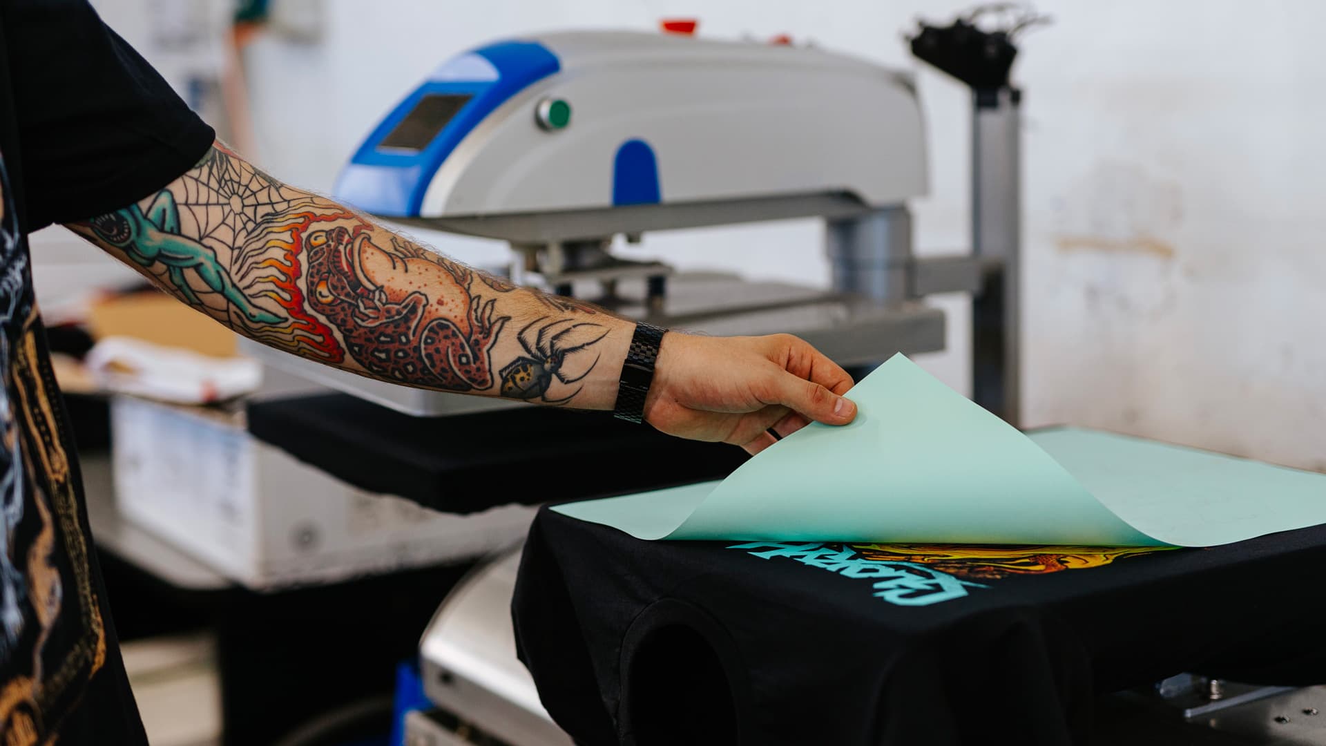 Peeling protective transfer sheet from vibrant heat-pressed band t-shirt design